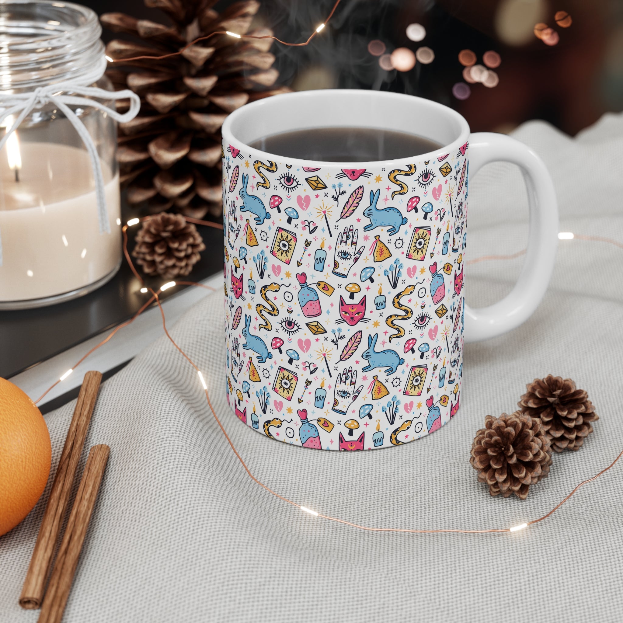 Patterned mug with decorative elements on a table with candles and pinecones.