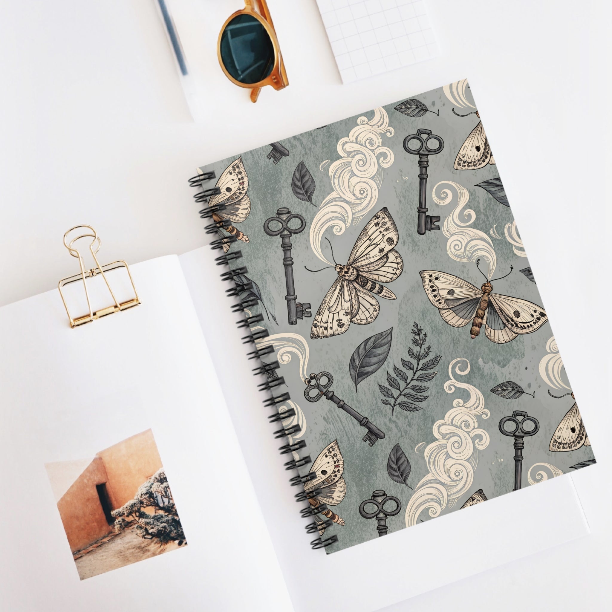 Notebook with moth and key design on a white surface