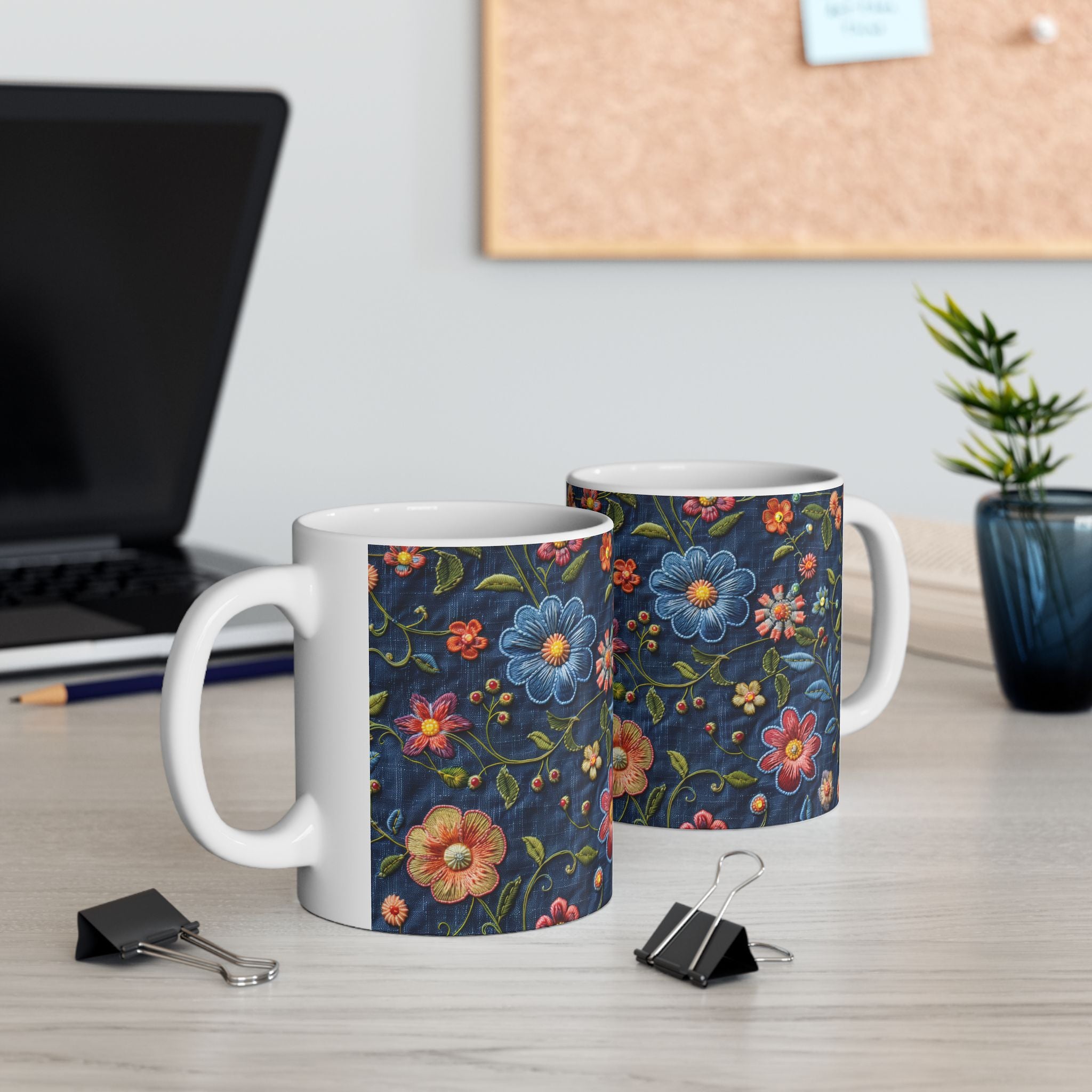 Two mugs with floral patterns on a desk with office items.