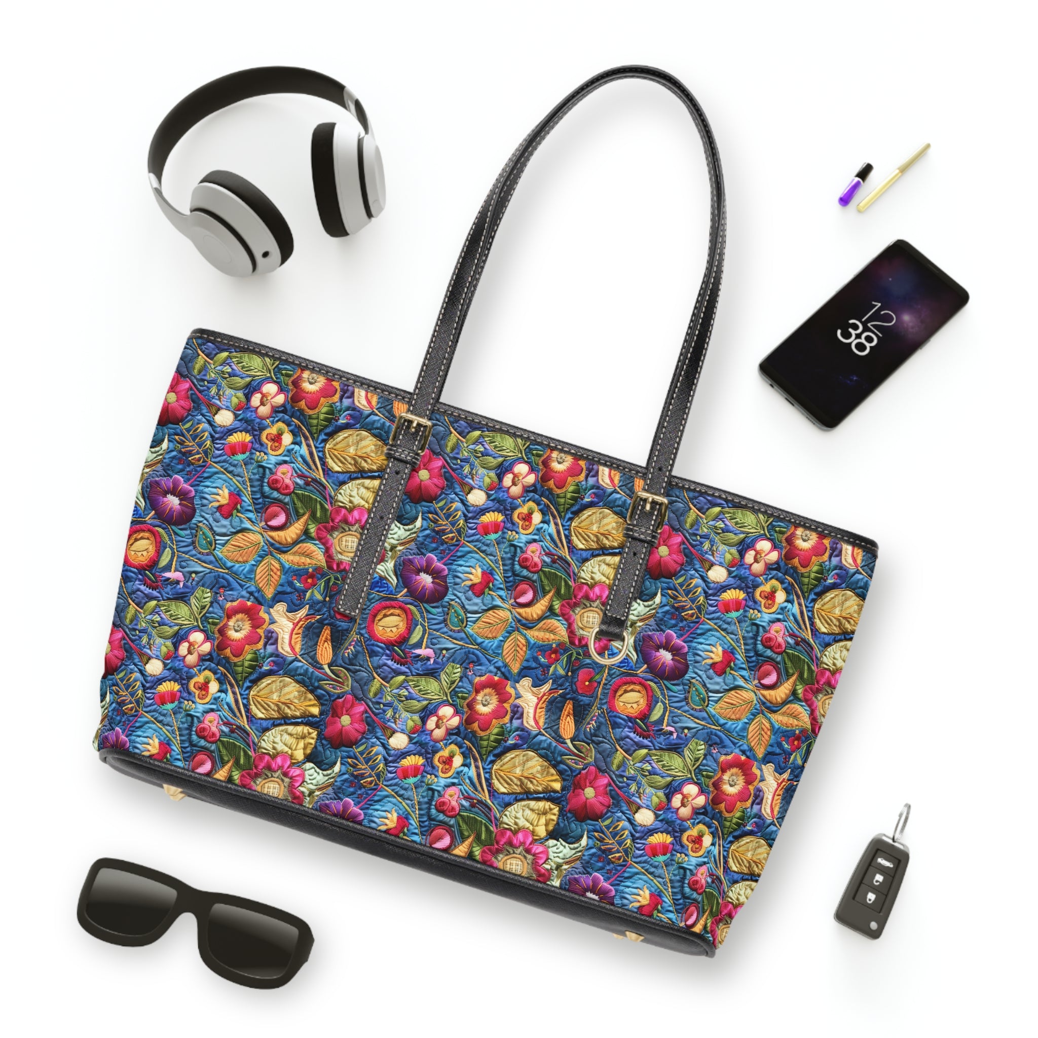 Colorful floral-patterned handbag with accessories on a white background