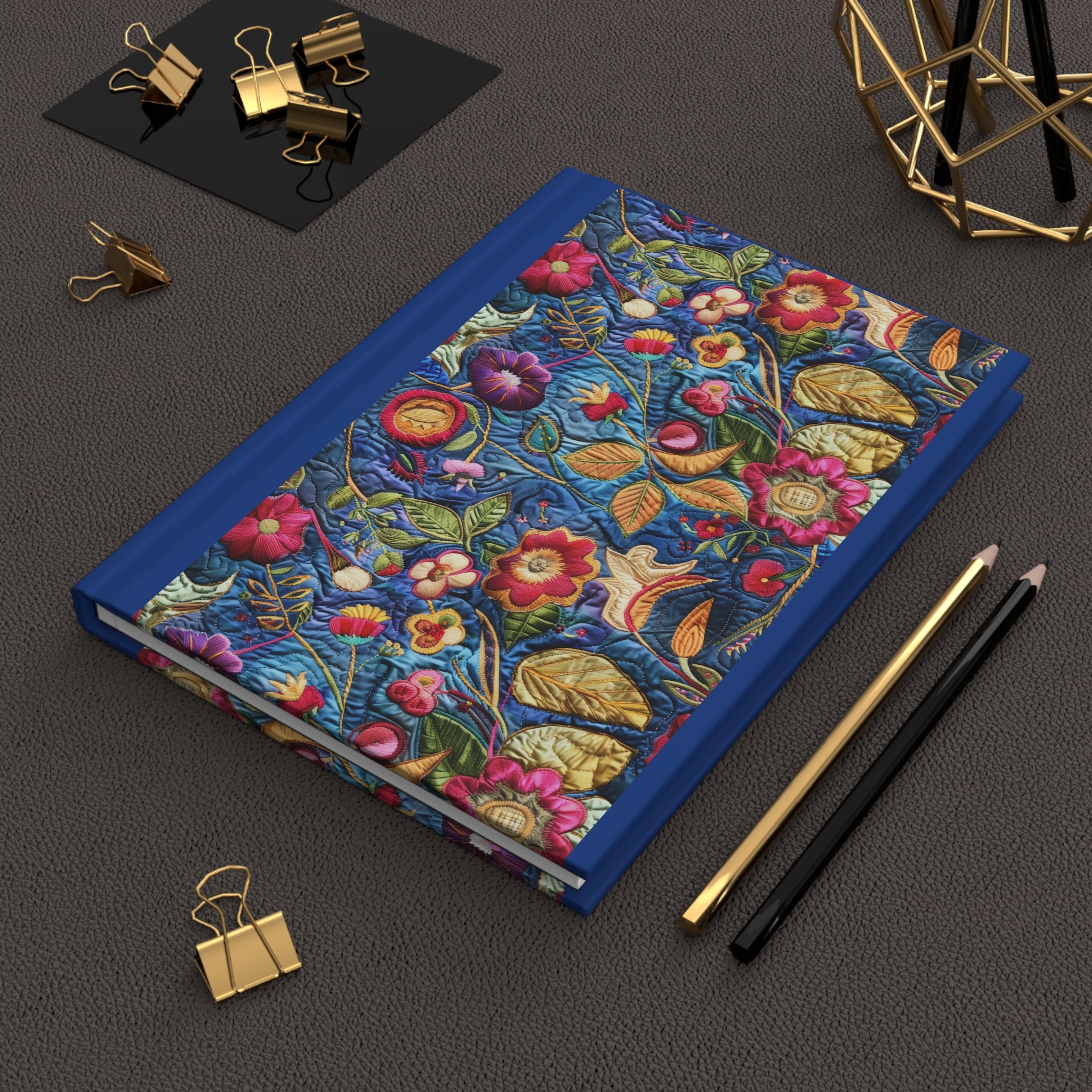 Floral notebook with decorative elements on a dark surface with stationery items.