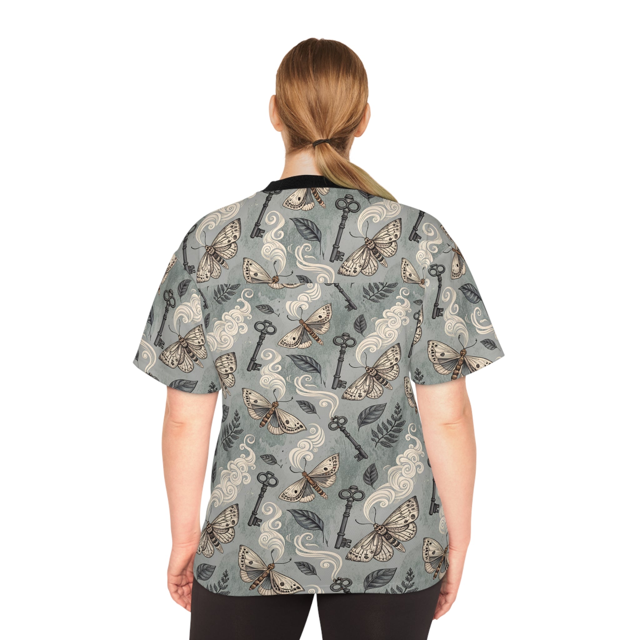 Person wearing a patterned shirt with keys and moths on a white background