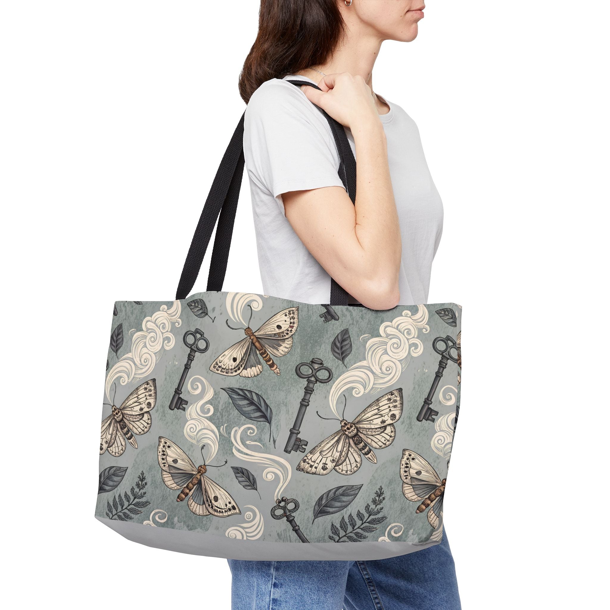 Model carrying a tote bag with moth and key design on a white background