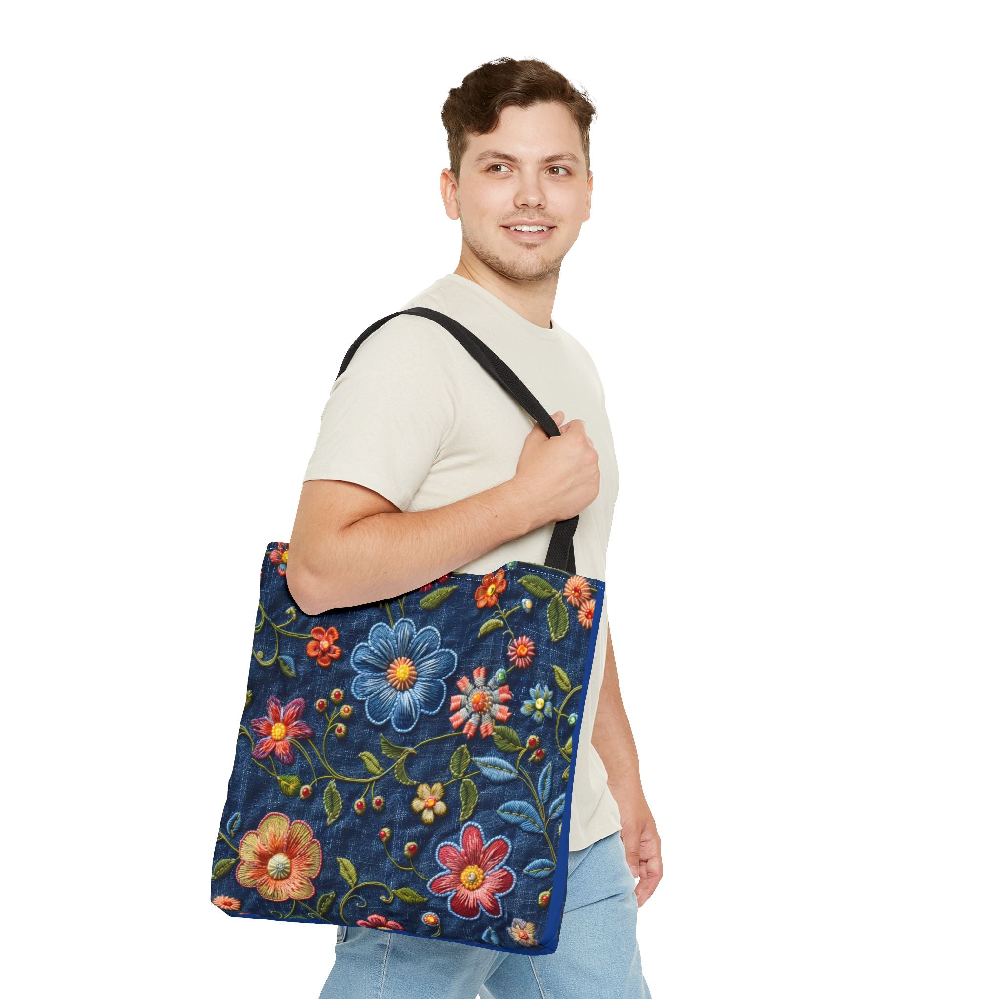 Man holding a blue tote bag with floral embroidery on a white background
