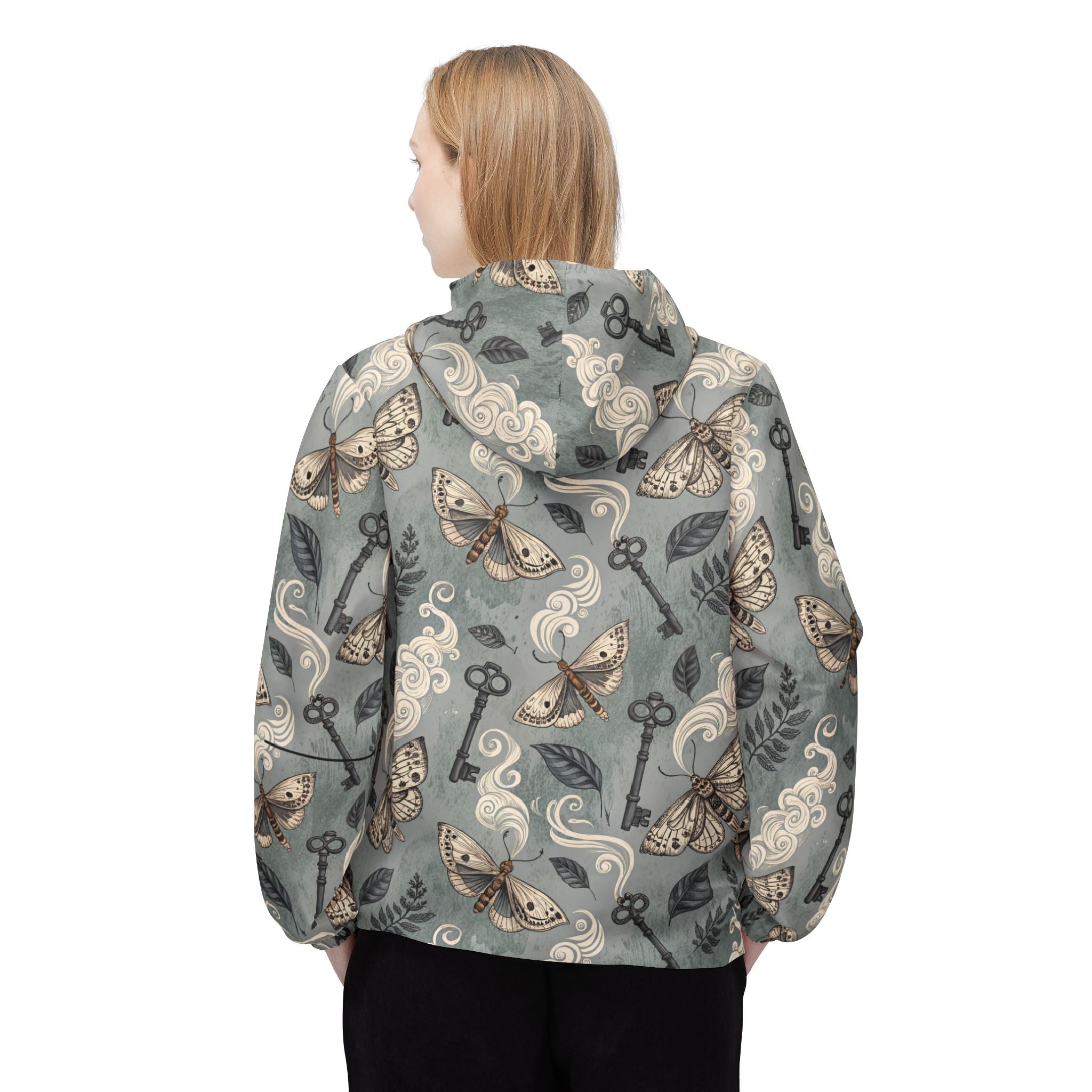 Person wearing a patterned jacket with keys, butterflies, and swirls on a white background