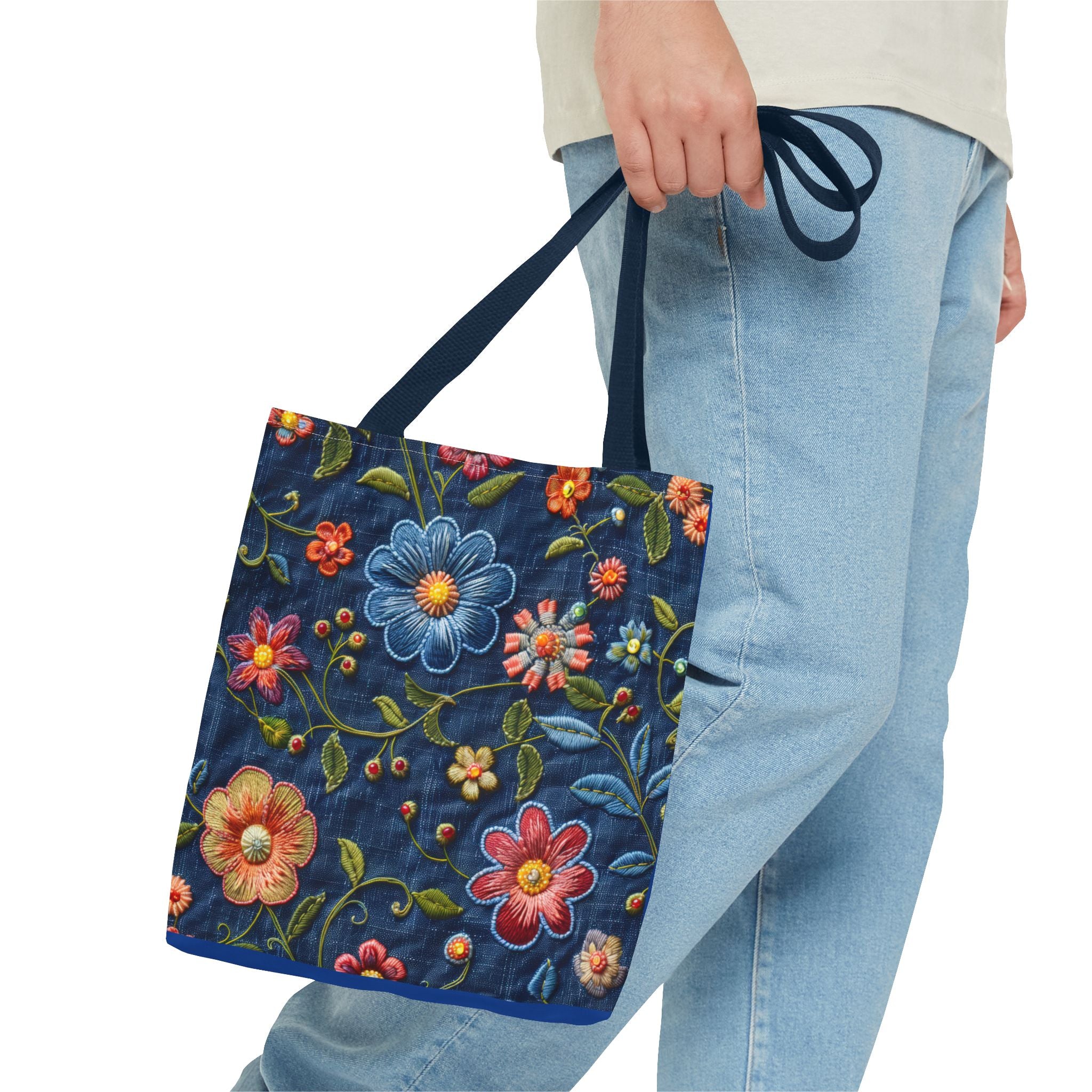 Person holding a blue tote bag with floral embroidery on a white background