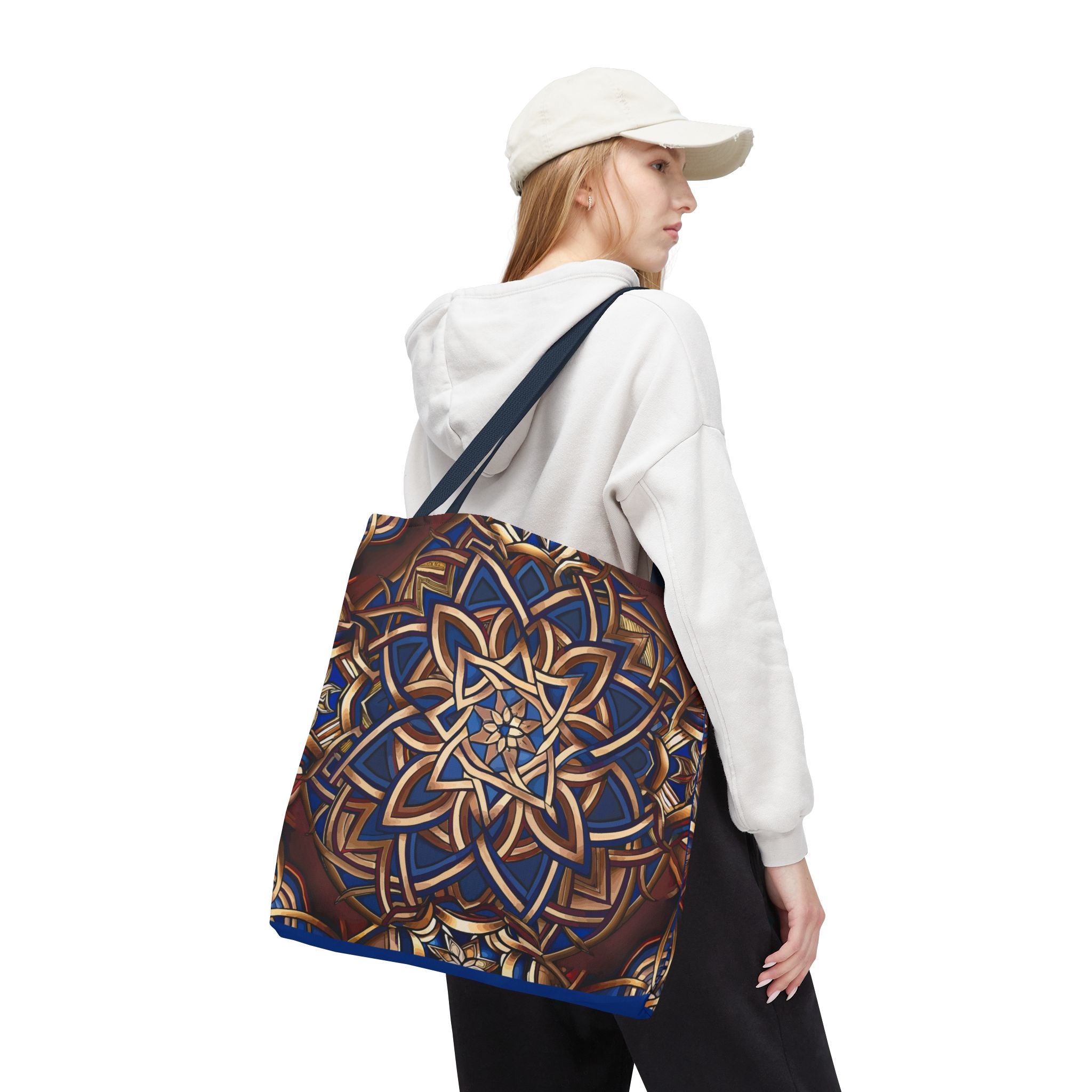 Person wearing a white hoodie and cap, carrying a large blue and gold Celtic knot bag on a white background