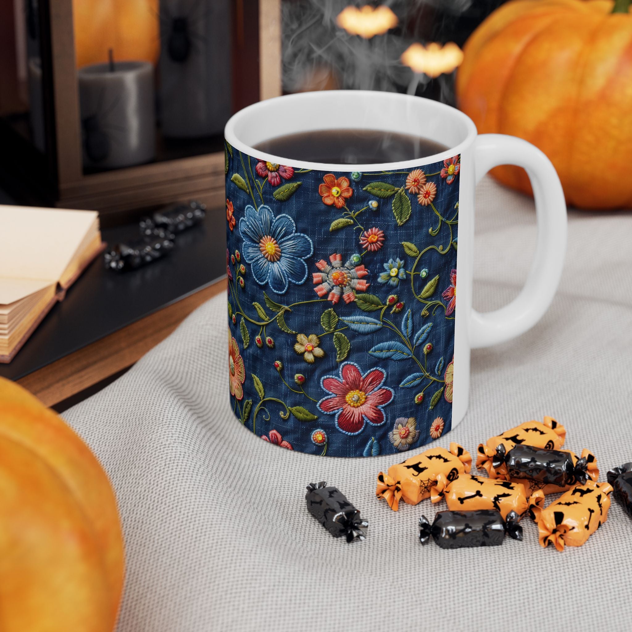 Mug with floral design on a table with Halloween-themed treats and pumpkins.