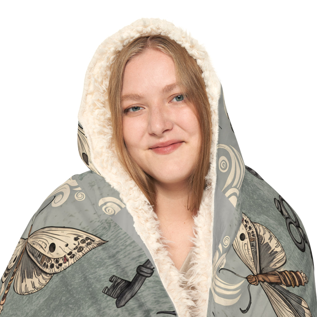 Hooded blanket with moth and key pattern on a white background