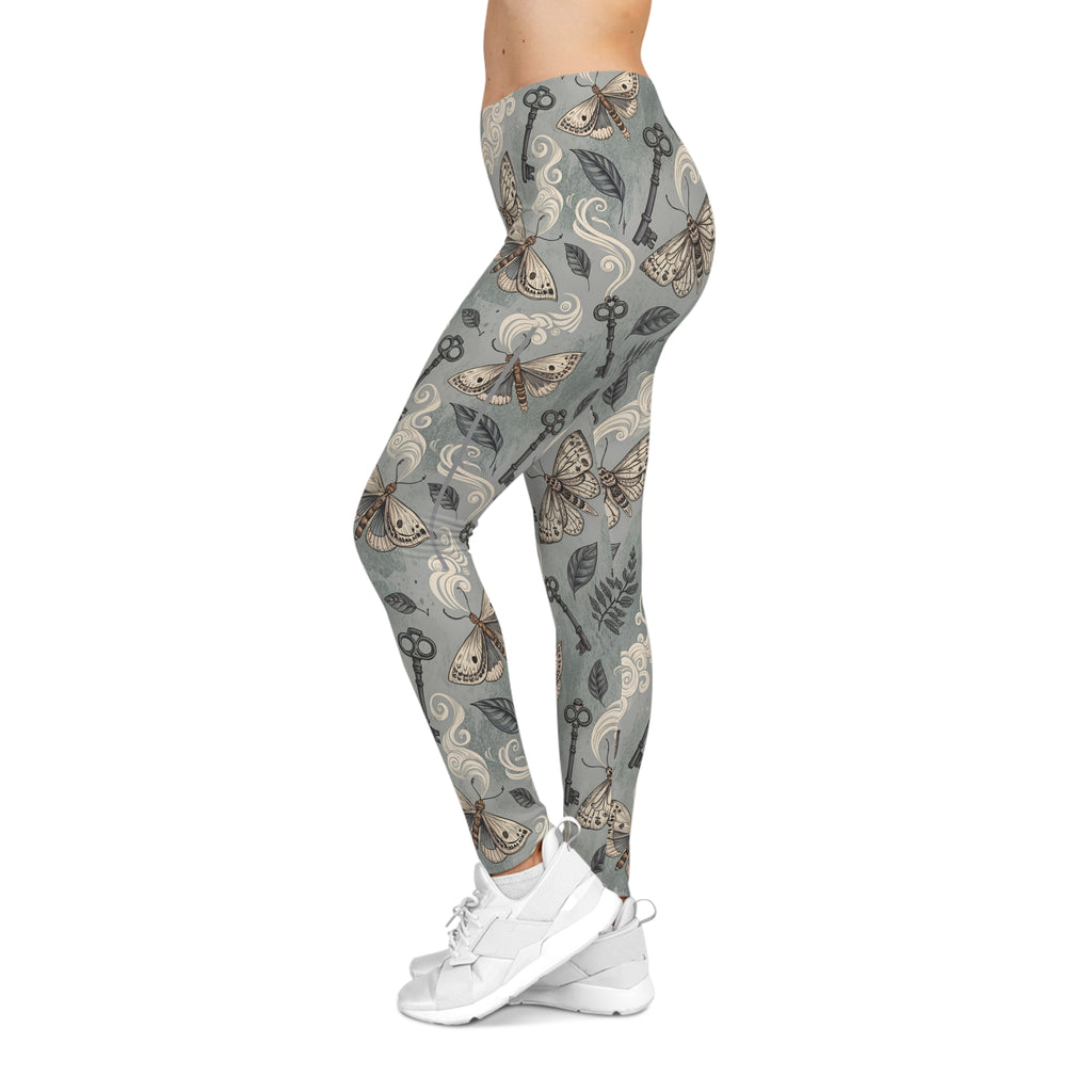 Leggings with a pattern of keys, moths  and nature elements on a gray background, worn by a model.