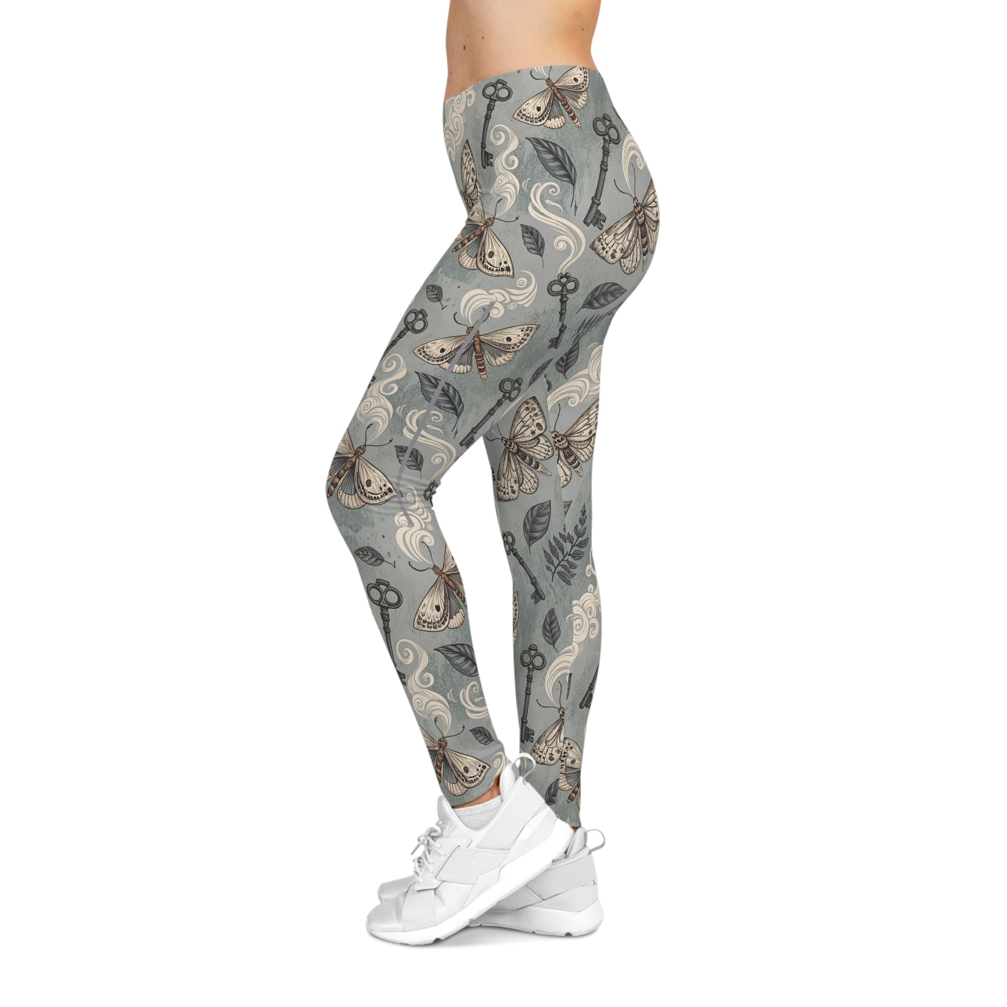 Leggings with a pattern of keys, moths  and nature elements on a gray background, worn by a model.