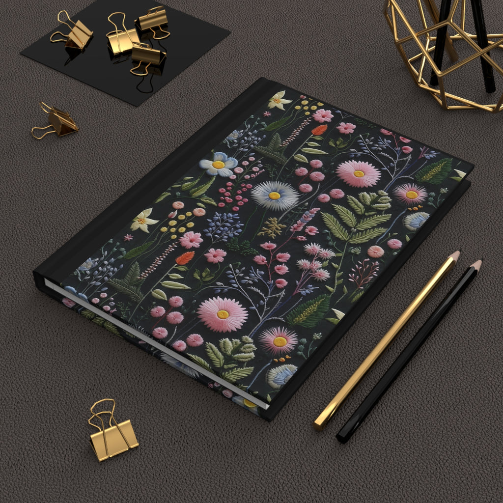 Floral notebook on a dark surface with stationery items