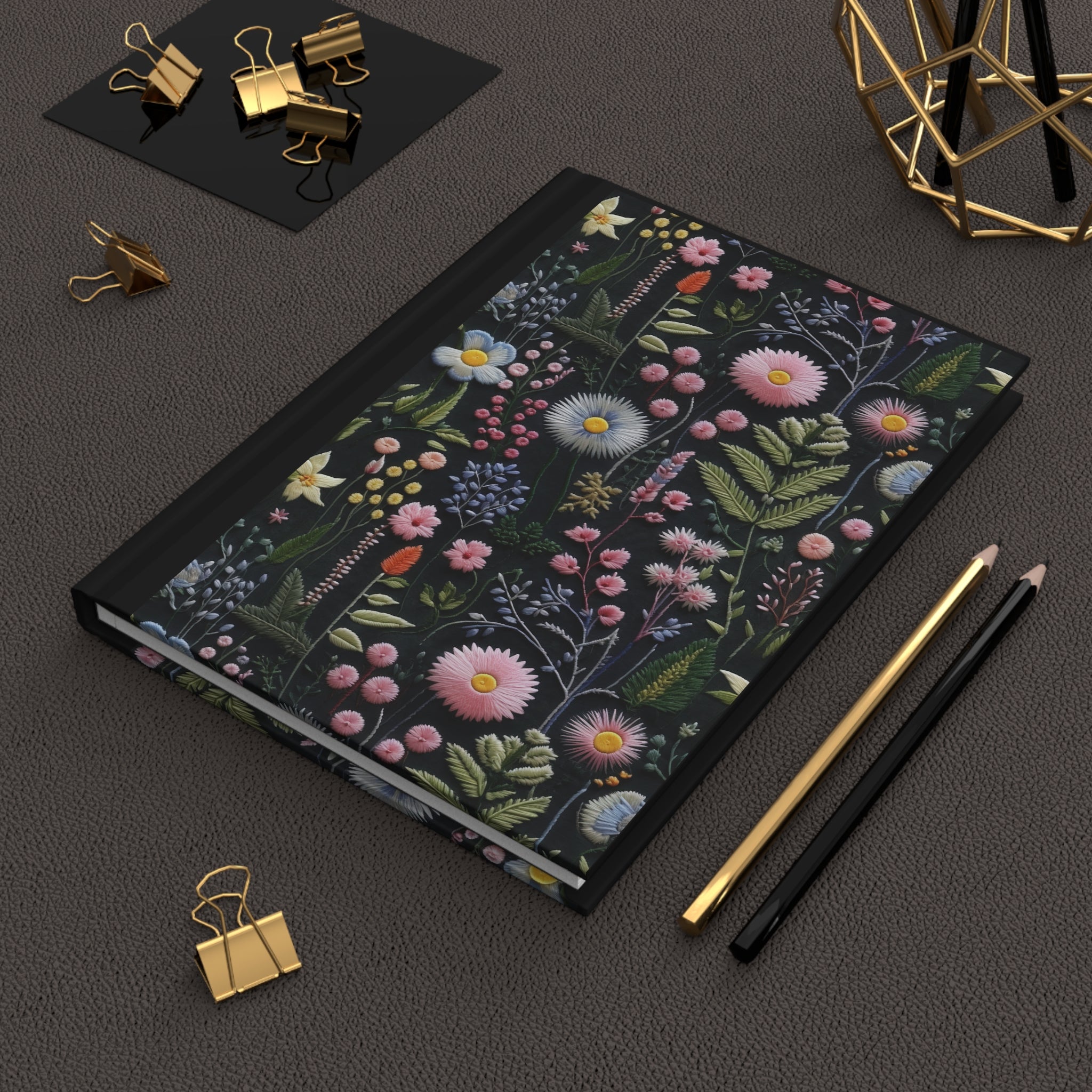 Floral notebook on a dark surface with stationery items
