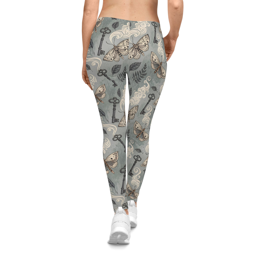 Leggings with a pattern of keys, moths, and leaves on a gray background.
